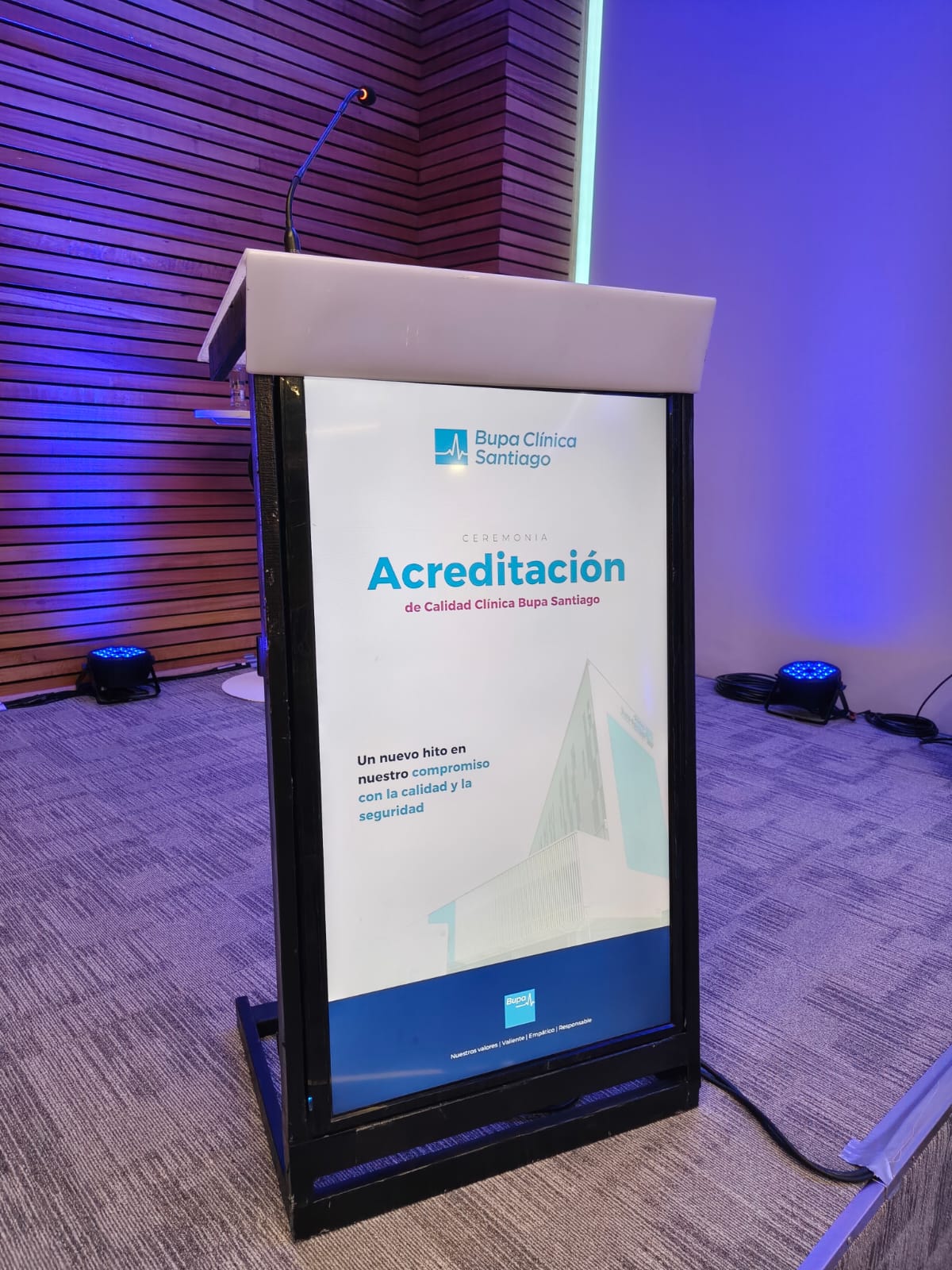Pódium multimedia con pantalla frontal vertical que muestra una gráfica de acreditación de Clínica Bupa Santiago